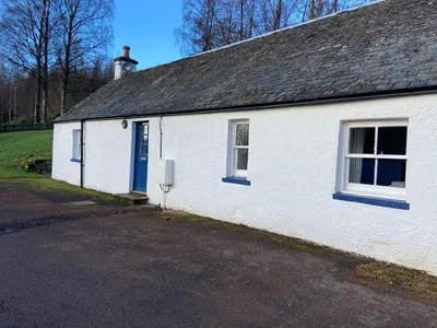 a white building with a blue door and windows at Fordie West Cottage in Comrie