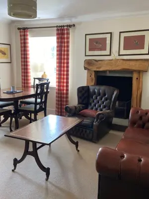 a living room with a table and a fireplace at Fordie West Cottage in Comrie