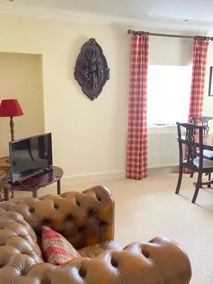 a living room with a brown leather couch and a table at Fordie West Cottage in Comrie
