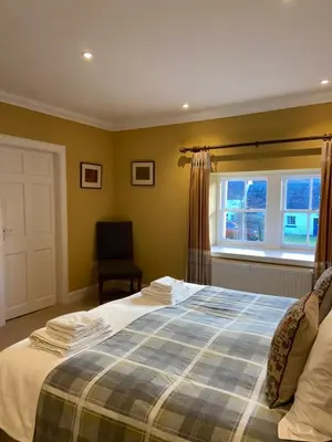 a bedroom with a bed and a chair and a window at Fordie West Cottage in Comrie