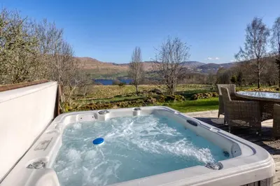 a jacuzzi tub sitting on a patio with a table at Oak Cottage and Hot Tub, Loch Tay in Lawers