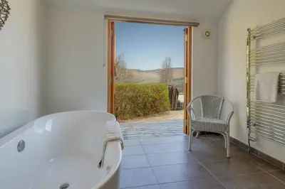 a bathroom with a tub and a chair and a window at Oak Cottage and Hot Tub, Loch Tay in Lawers