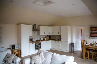 a living room with a couch and a kitchen at Oak Cottage and Hot Tub, Loch Tay in Lawers
