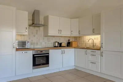 a white kitchen with white cabinets and a sink at Oak Cottage and Hot Tub, Loch Tay in Lawers