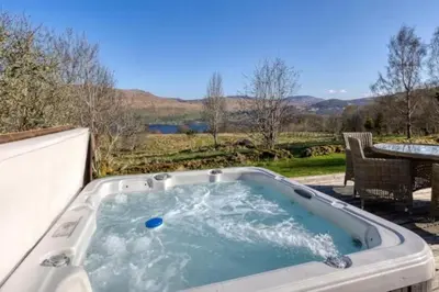 a jacuzzi tub on a patio with a table at Oak Cottage and Hot Tub, Loch Tay in Lawers