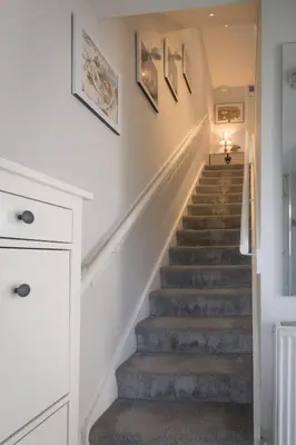 a staircase in a home with white walls and gray carpet at 2-Bedroom Home Away From Home in Glasgows' East End with FREE Parking in Mount Vernon