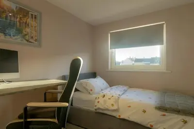 a bedroom with a bed and a desk and a chair at 2-Bedroom Home Away From Home in Glasgows' East End with FREE Parking in Mount Vernon