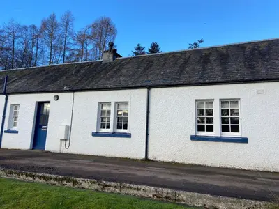 a white building with a blue door and windows at Fordie East Cottage in Comrie