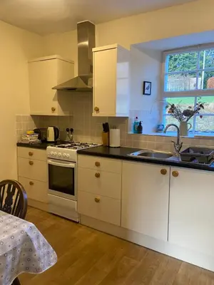 a kitchen with white cabinets and a sink and a window at Fordie East Cottage in Comrie