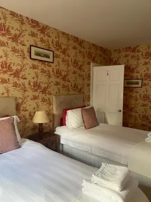two beds in a room with wallpaper at Fordie East Cottage in Comrie