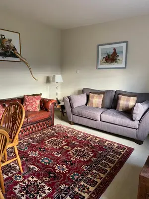 a living room with two couches and a rug at Fordie East Cottage in Comrie