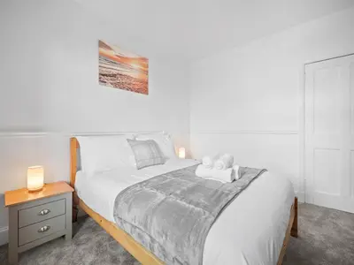 a bedroom with a large bed and a nightstand with a bed sidx sidx sidx at Whiteside 3 Bedroom Apartment - Bathgate in Bathgate