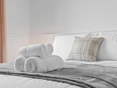 a pile of towels sitting on top of a bed at Whiteside 3 Bedroom Apartment - Bathgate in Bathgate