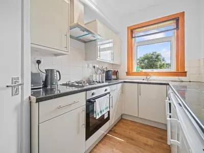 a kitchen with white cabinets and a window at Whiteside 3 Bedroom Apartment - Bathgate in Bathgate
