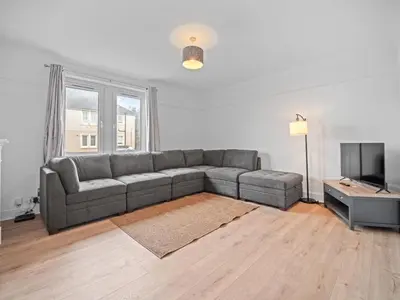 a living room with a gray couch and a television at Mollison 2 Bedroom Apartment - Harthill in Harthill