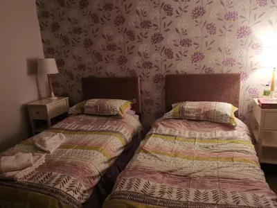 two beds in a small room with wallpaper at Kings Arms Holiday Apartments in Oban