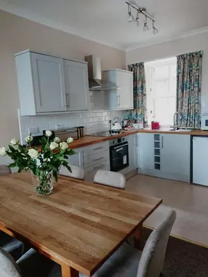 a kitchen with a wooden table with a vase of flowers on it at Kings Arms Holiday Apartments in Oban