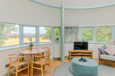 a living room with a table and chairs and a tv at Retreat to the Water Tower in Queensferry
