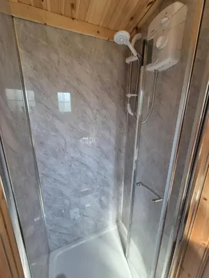 a shower with a glass door in a bathroom at Blair snug hut 2 in Kelty