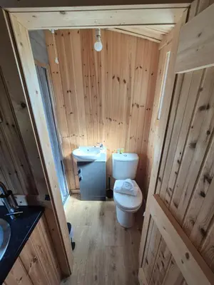 a wooden bathroom with a toilet and a sink at Blair snug hut 2 in Kelty
