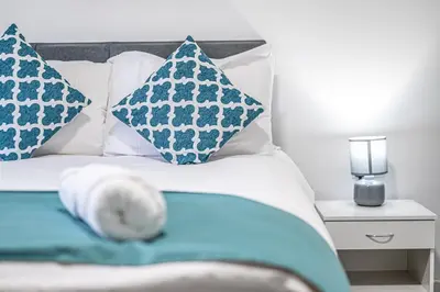 a bed with blue and white pillows on it at City Centre Apartment in Dunfermline