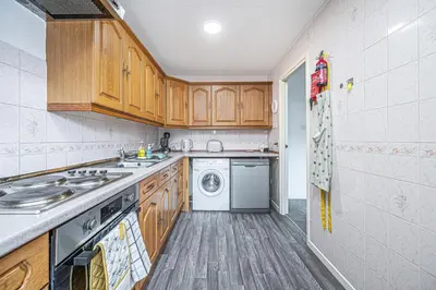 a kitchen with wooden cabinets and a washer and dryer at City Centre Apartment in Dunfermline