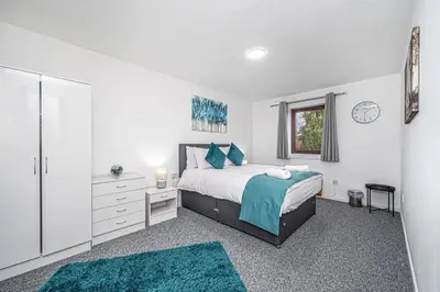 a bedroom with a bed and two turquoise rugs at City Centre Apartment in Dunfermline