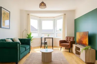 a living room with a green couch and a chair at Walk to Hydro and SEC Modern 3BR Free Parking in Glasgow