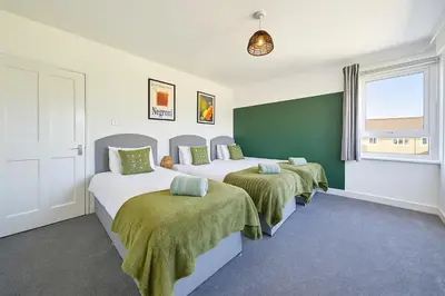 a bedroom with three beds with green and white at Walk to Hydro and SEC Modern 3BR Free Parking in Glasgow