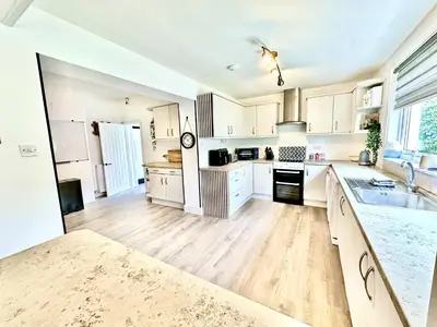 a large kitchen with white cabinets and a wooden floor at Avenue Cottage, Inveraray in Inveraray