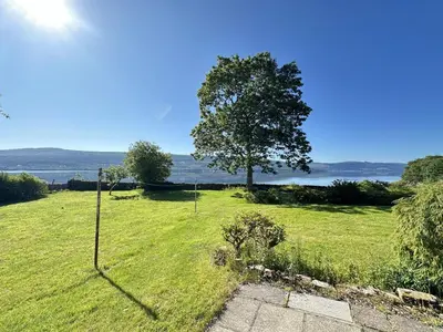 a field of grass with a tree in the background at Avenue Cottage, Inveraray in Inveraray