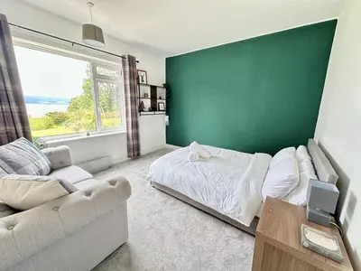 a bedroom with a green wall and a bed and a couch at Avenue Cottage, Inveraray in Inveraray