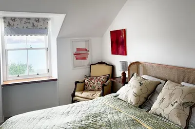 a bedroom with a bed and a chair and a window at Old Schoolhouse in Inveraray