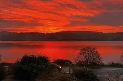 a sunset over a lake with a red sky at Old Schoolhouse in Inveraray