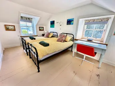 two beds in a room with a desk and two windows at Old Schoolhouse in Inveraray