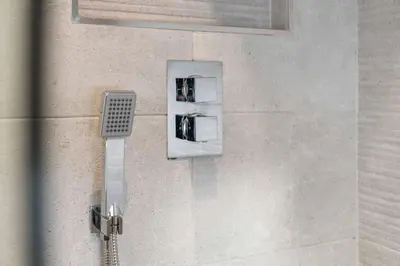 a shower with aaucet on a wall at Kirkstyle Cottage in Coatbridge