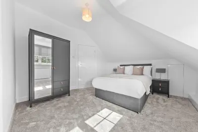 a white bedroom with a bed and a mirror at Kirkstyle Cottage in Coatbridge