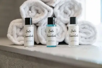 three bottles of soap on a shelf with towels at Kirkstyle Cottage in Coatbridge
