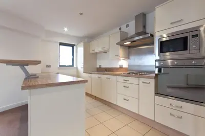 a kitchen with white cabinets and stainless steel appliances at Waterfront Spacious Flat in Edinburgh