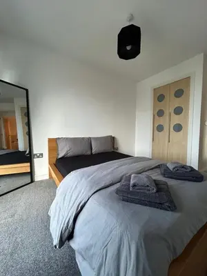 a bedroom with a large bed and a mirror at Waterfront Spacious Flat in Edinburgh