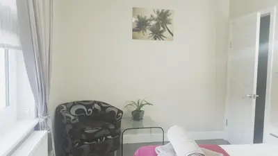 a bedroom with a black chair and a plant at My Glasgow House Bishopbriggs in Bishopbriggs