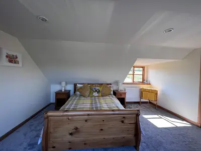 a bedroom with a wooden bed in a attic at Easter Auchencarroch Farm B&B in Balloch
