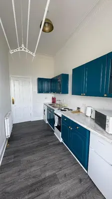 a kitchen with blue cabinets and white counter tops at Seaview apartment in Rothesay in Rothesay