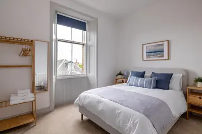 a white bedroom with a bed and a window at Antonine Quarters in Grahamston