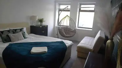 a bedroom with a bed and a chair and a window at gourock blissful apartment with 3 bedrooms in Gourock