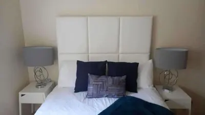a bedroom with a bed with two lamps on it at gourock blissful apartment with 3 bedrooms in Gourock