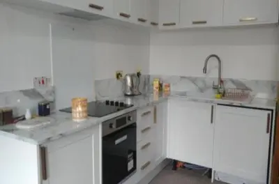 a kitchen with white cabinets and a stove top oven at gourock blissful apartment with 3 bedrooms in Gourock