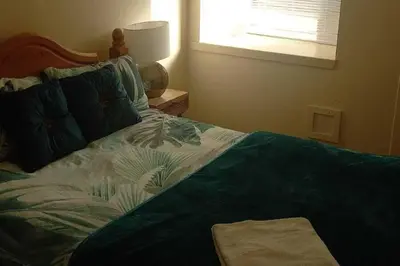 a bedroom with a bed with a green blanket and a window at gourock blissful apartment with 3 bedrooms in Gourock