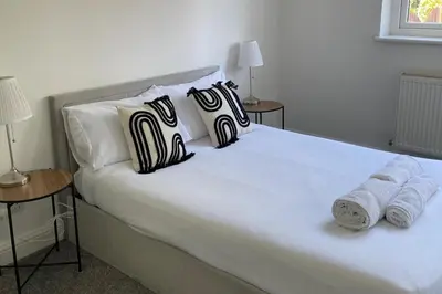 a white bed with black and white pillows on it at Glasgow City Apartment with 2 Bedrooms in Glasgow