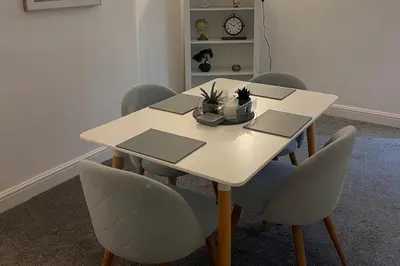 a white dining room table with chairs and a clock at Glasgow City Apartment with 2 Bedrooms in Glasgow